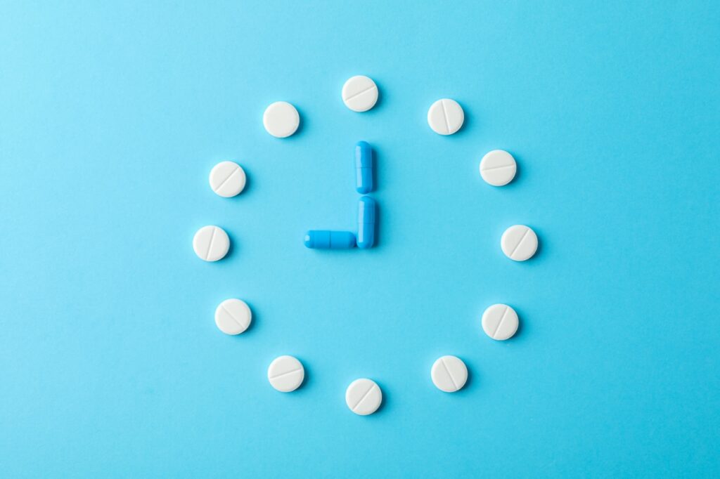 clock made of pills on blue background - how long for antidepressants to work?